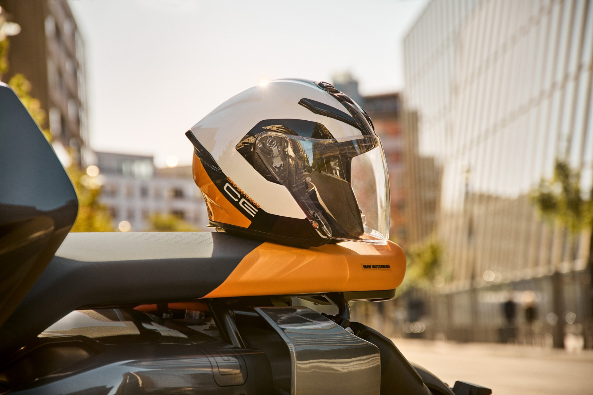 Cască BMW Motorrad așezată pe șaua unei motociclete, într-un decor urban