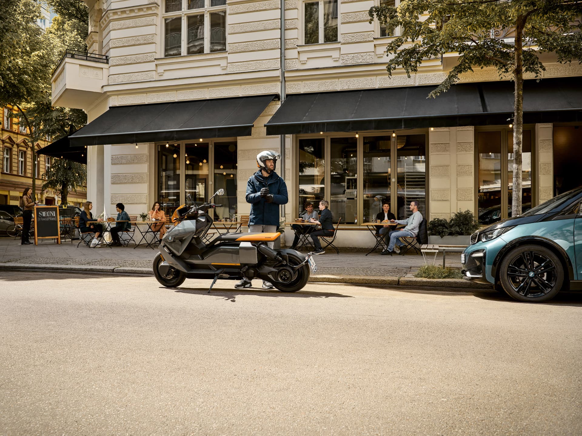 Motocicletă BMW Motorrad oprită pe o stradă din oraș, lângă terasa unei cafenele